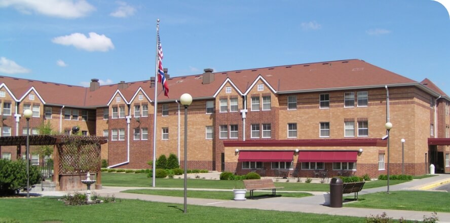 Exterior of the Como Park senior living campus featuring a well-maintained courtyard with greenery, benches, and a pergola.