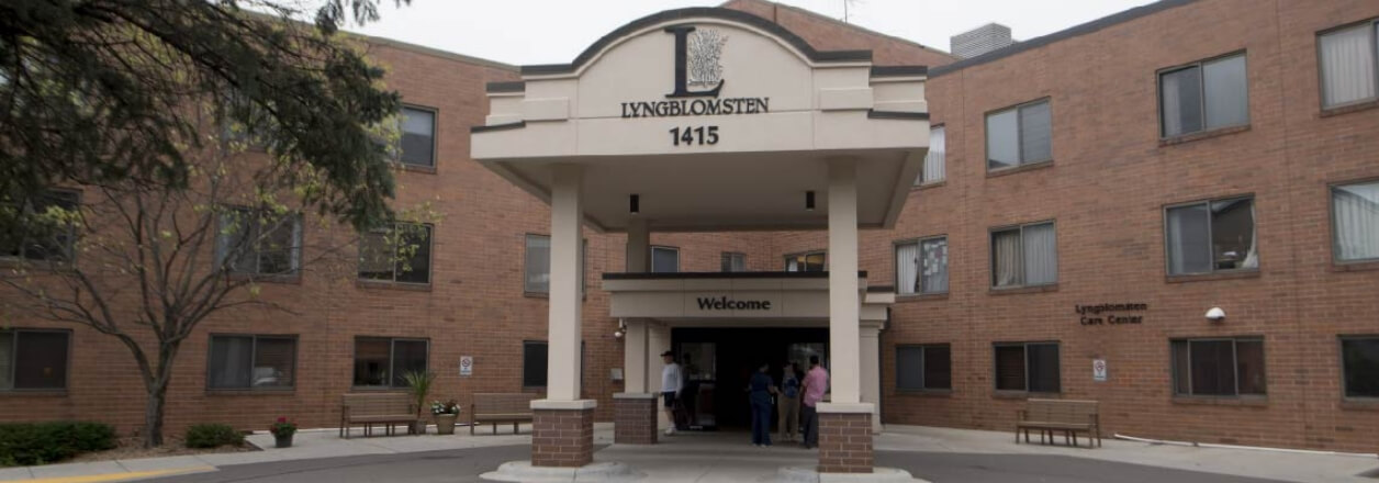 Entrance of the Lyngblomsten Care Center at Como Park, featuring a covered entryway with people entering the facility.