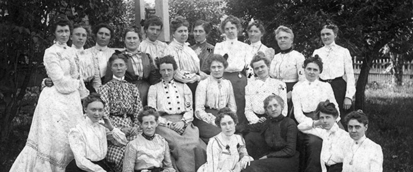Historical photo of Lyngblomsten's women founders in 1910, dressed in period attire and gathered outdoors.