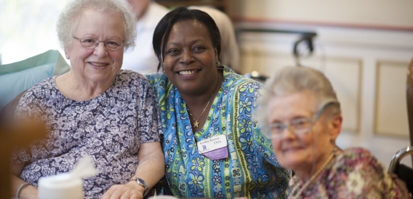 Caregiver with two older adult women at a senior care facility