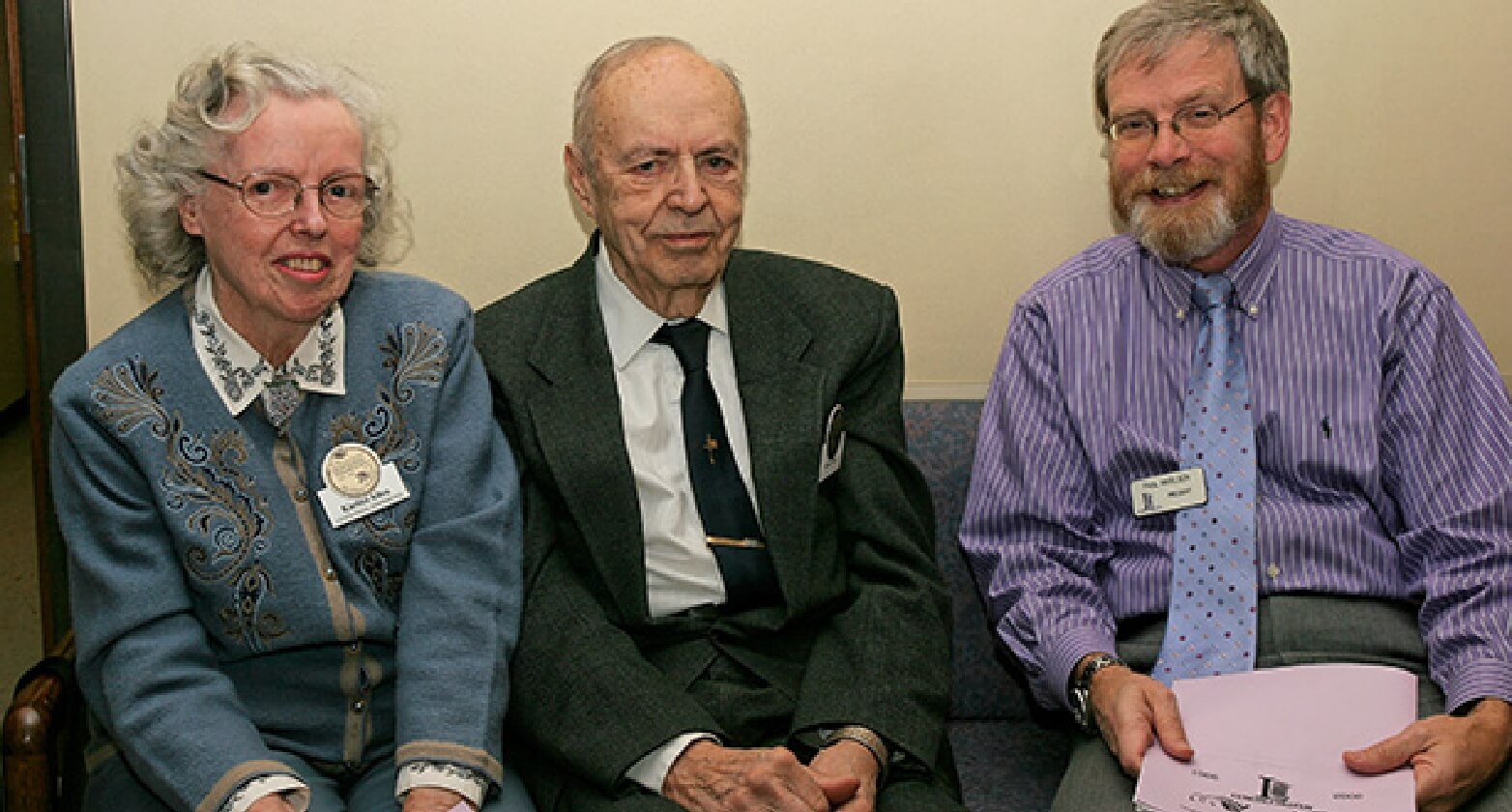 Three individuals sitting together, including Karina Allen, engaged in conversation and holding documents.