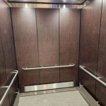 Interior of the Lyngblomsten Lino Lakes senior living elevator, featuring wood panel walls, handrails, and soft lighting.