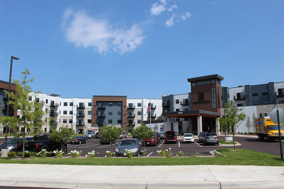 Exterior view of the Lyngblomsten Lino Lakes senior living community, featuring modern apartments, parking, and landscaped surroundings.