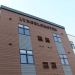 Exterior view of the Lyngblomsten senior living building at Lino Lakes, showcasing modern architectural design with wood and white paneling.