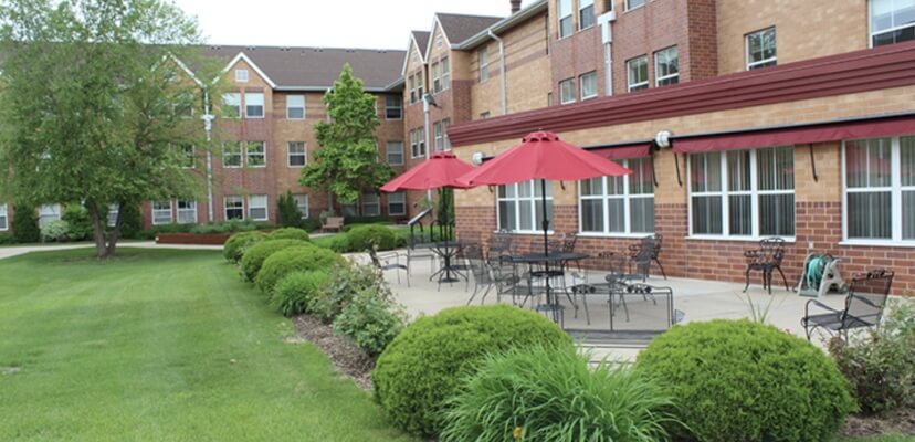 Outdoor patio with red umbrellas and seating at Lyngblomsten senior housing