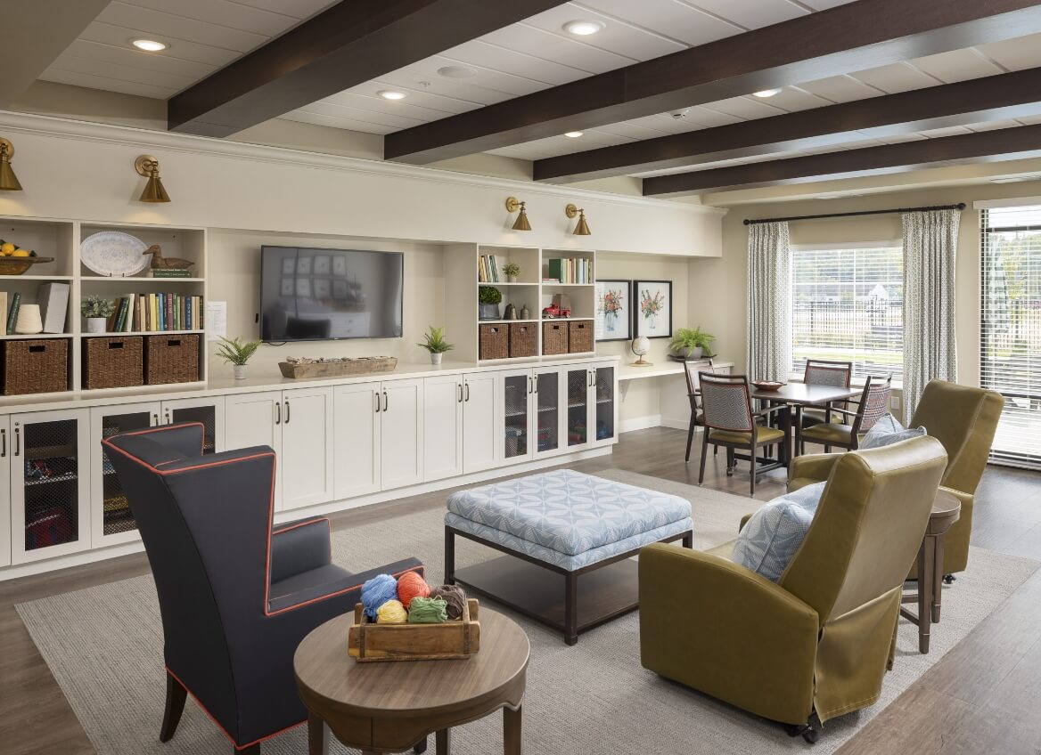 Activity room with TV, bookcases, and seating in Memory Care
