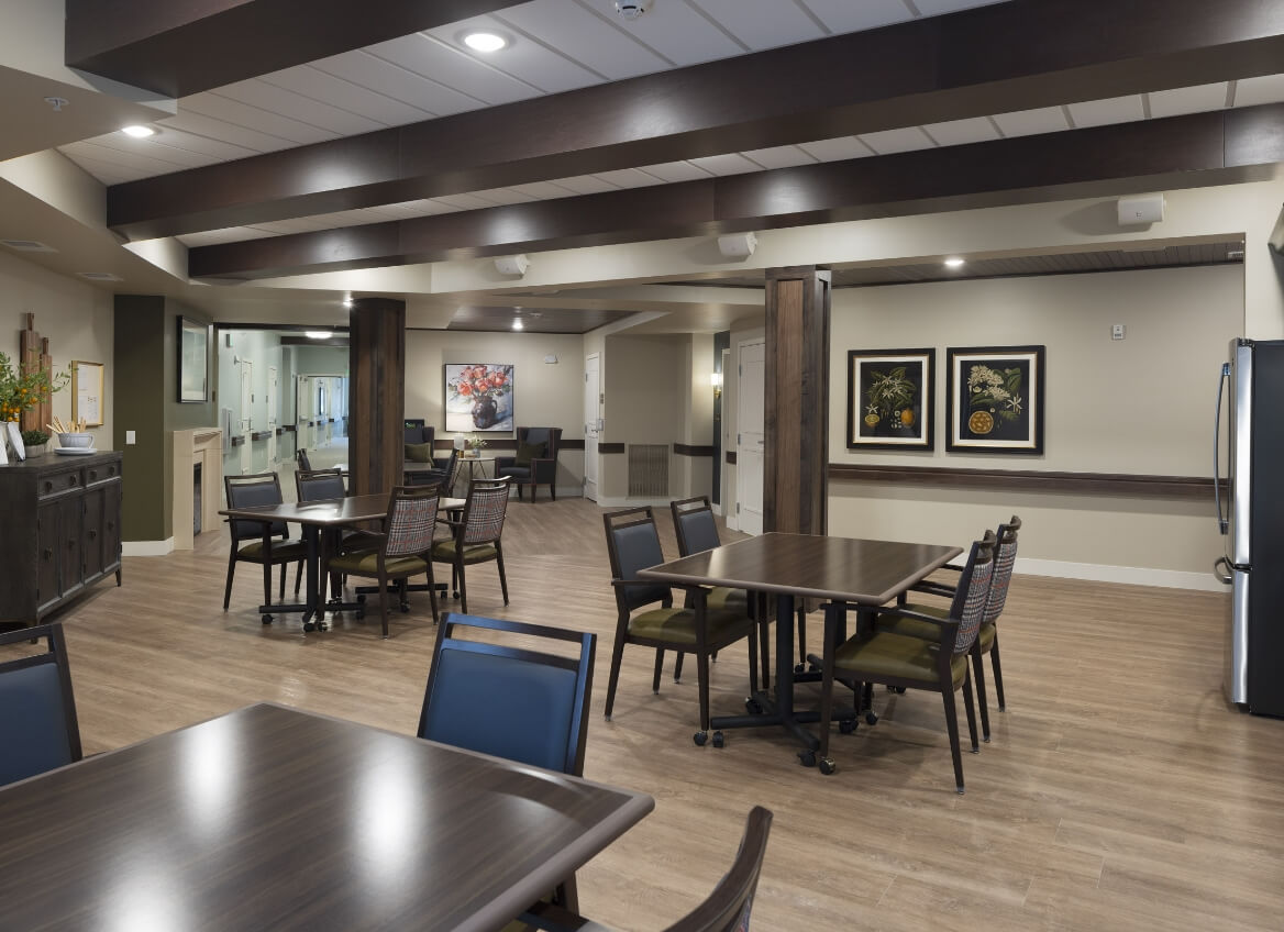 Memory Care dining and gathering space with dark tables and beams