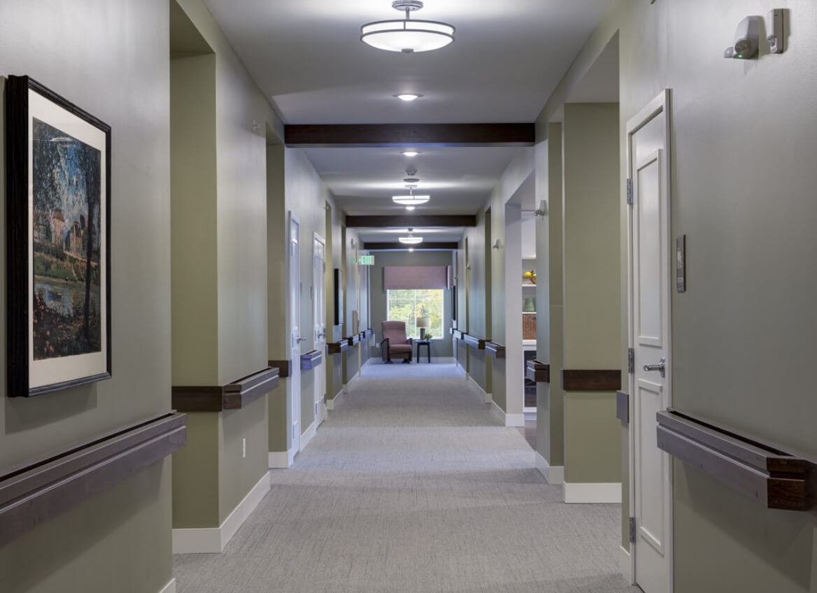 Well-lit Memory Care hallway with artwork and handrails