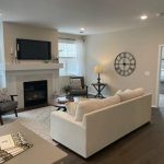 A modern senior living apartment living room at Lino Lakes, featuring a cozy fireplace, neutral-colored sofa, stylish decor, and an open layout leading to the bedroom.