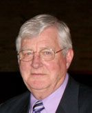 Portrait of Wally Hauge, former Lyngblomsten President & CEO (1980-1992), wearing a suit and tie with a solemn expression.