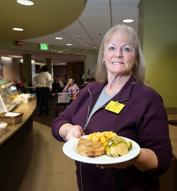 Lyngblomsten Volunteer poses with plated food from Anna's café and gifts that she served during her shift.