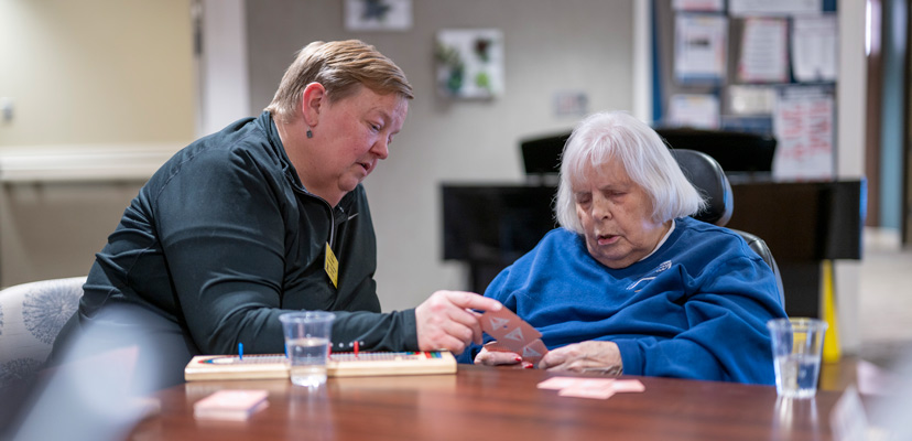 A Lyngblomsten volunteer and resident of the care center play cribbage together.
