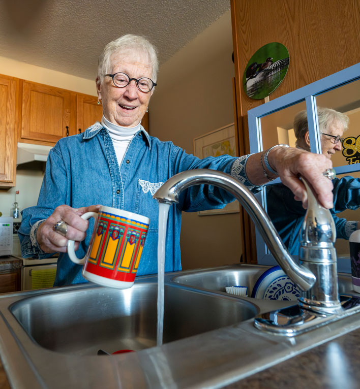 A resident fills her coffee mug up with water in her apartment.