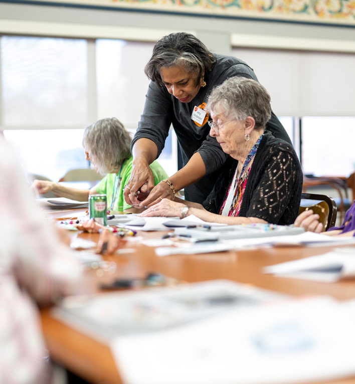 COMPAS teaching artist works with a resident on crafting a unique piece of jewelry at a class in the Lyngblomsten Apartments.