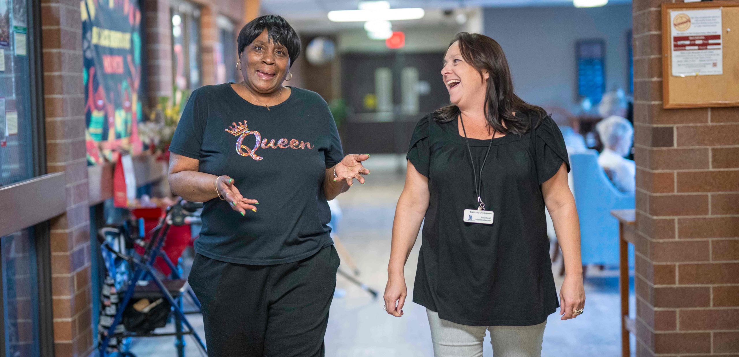 Resident and employee laughing as they walk down the hall in the Lyngblomsten Apartments.
