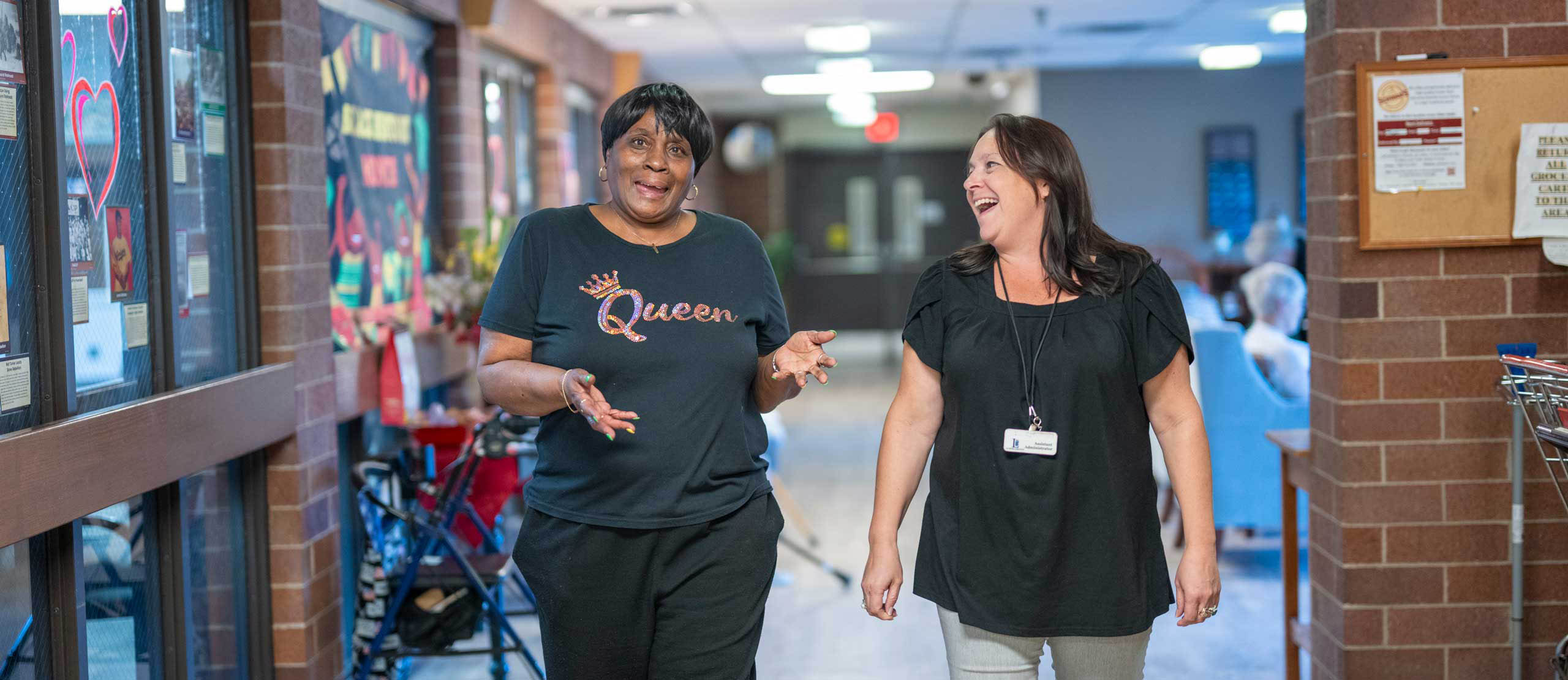 Resident and employee laughing as they walk down the hall in the Lyngblomsten Apartments.