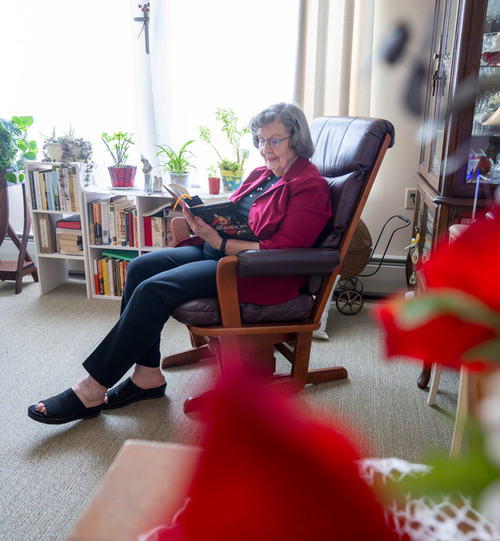 A resident of The Heritage at Lyngblomsten reads her book in the living room of her apartment.