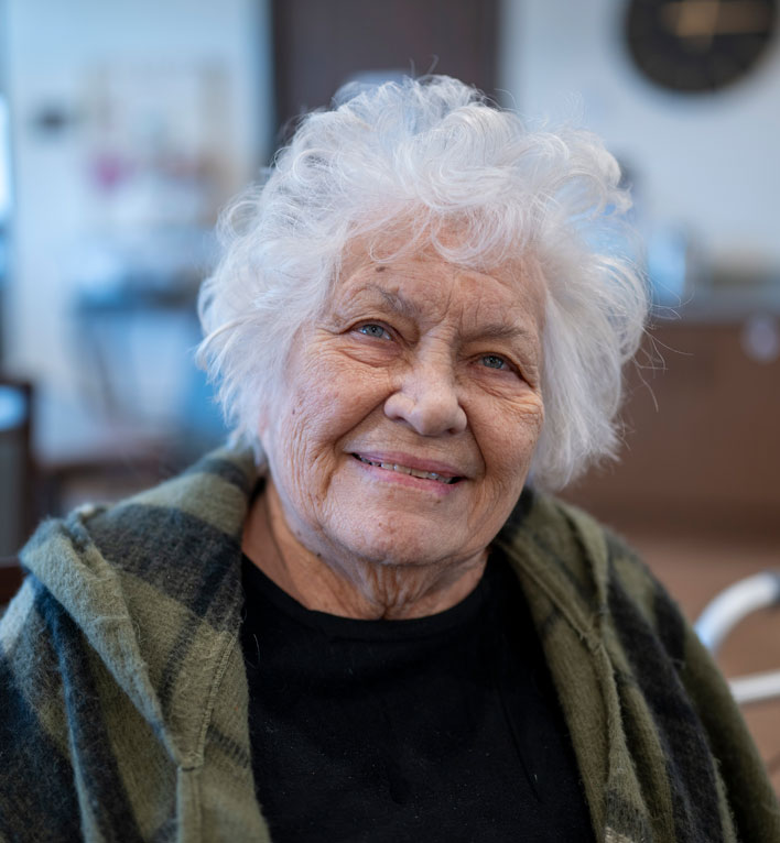 Resident on the Lyngblomsten at Lino Lakes campus smiles at the photographer as he captures his photo in Sophia's café and gift shop.