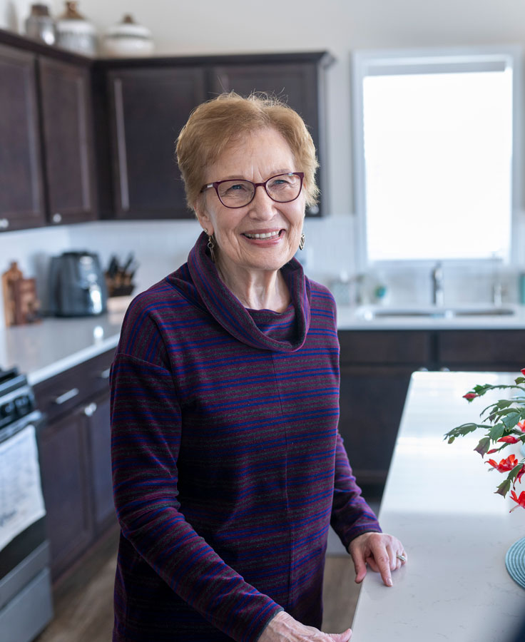 Townhome resident smiles into the camera from her kitchen.