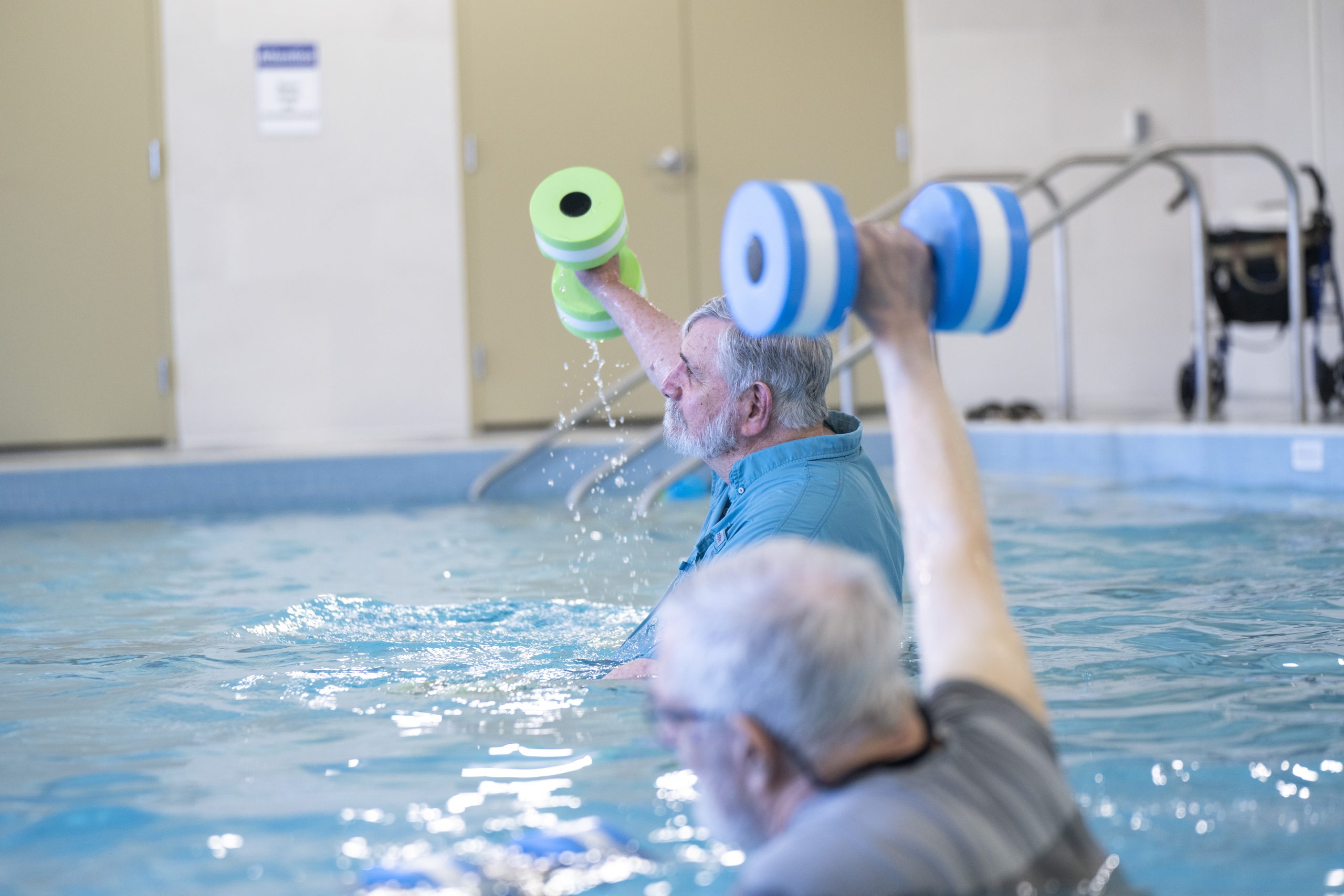 Two residents do water weight-lifting in the pool