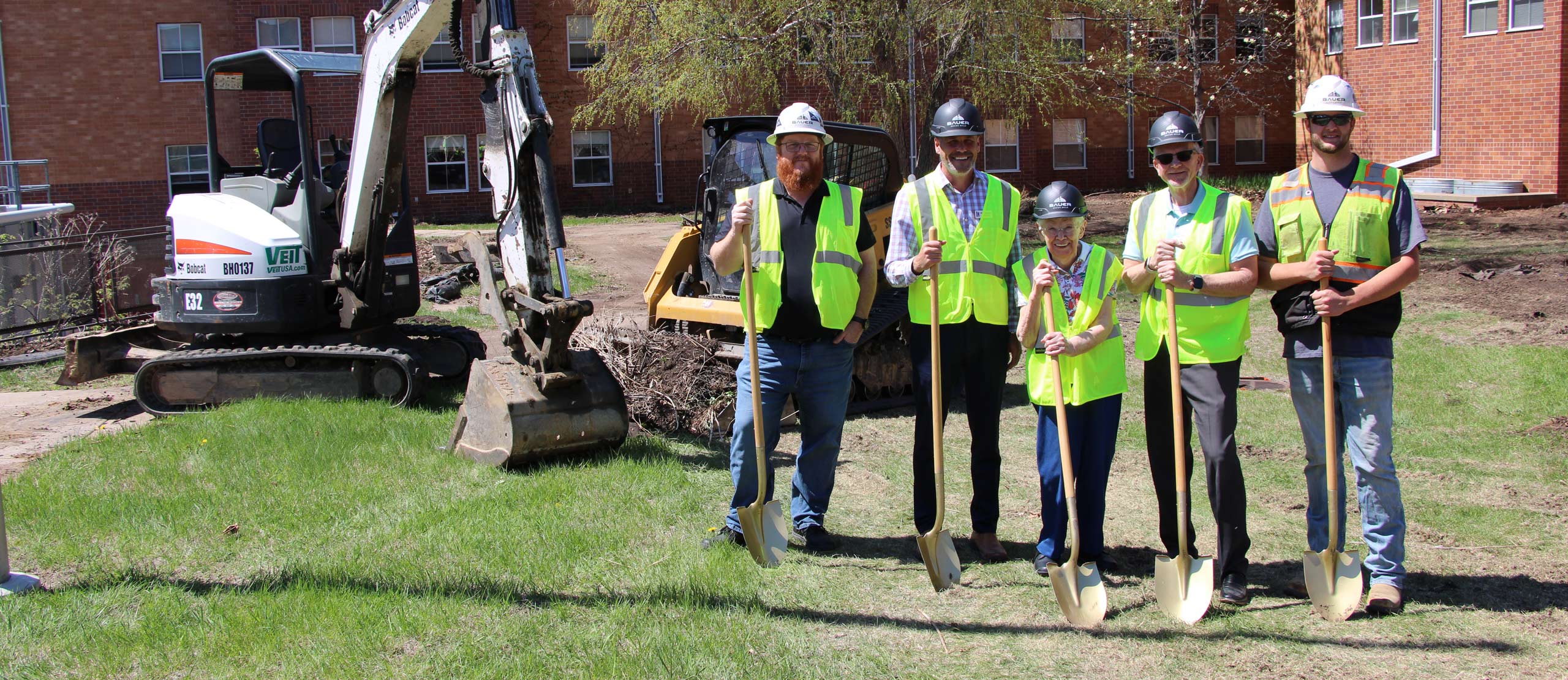 The courtyard ground breaking depicts heavy machinery and some demolition already underway in the background. The people pictured are construction workers, along with Lyngblomsten President & CEO, Lyngblomsten Foundation Executive Director, and a donor.