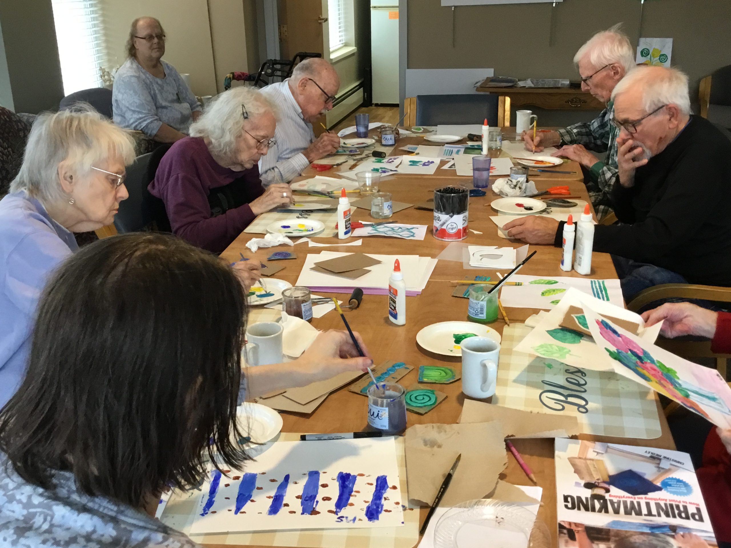 Wide shot photo of residents working on their projects through Art with Heart from The Heritage at Lyngblomsten