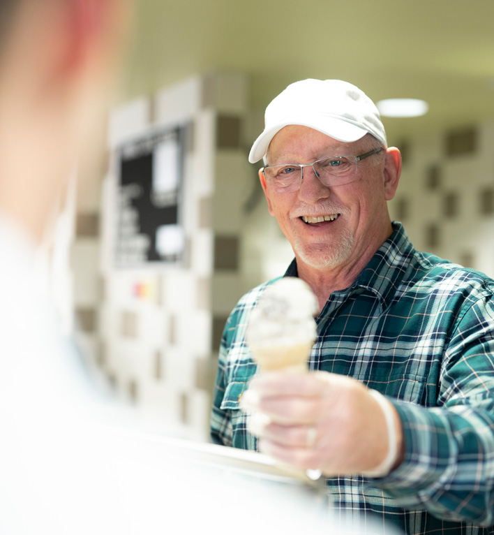 A Lyngblomsten Volunteer Hands an Employee an Ice Cream Cone from behind the Counter at Anna's cafe and gifts