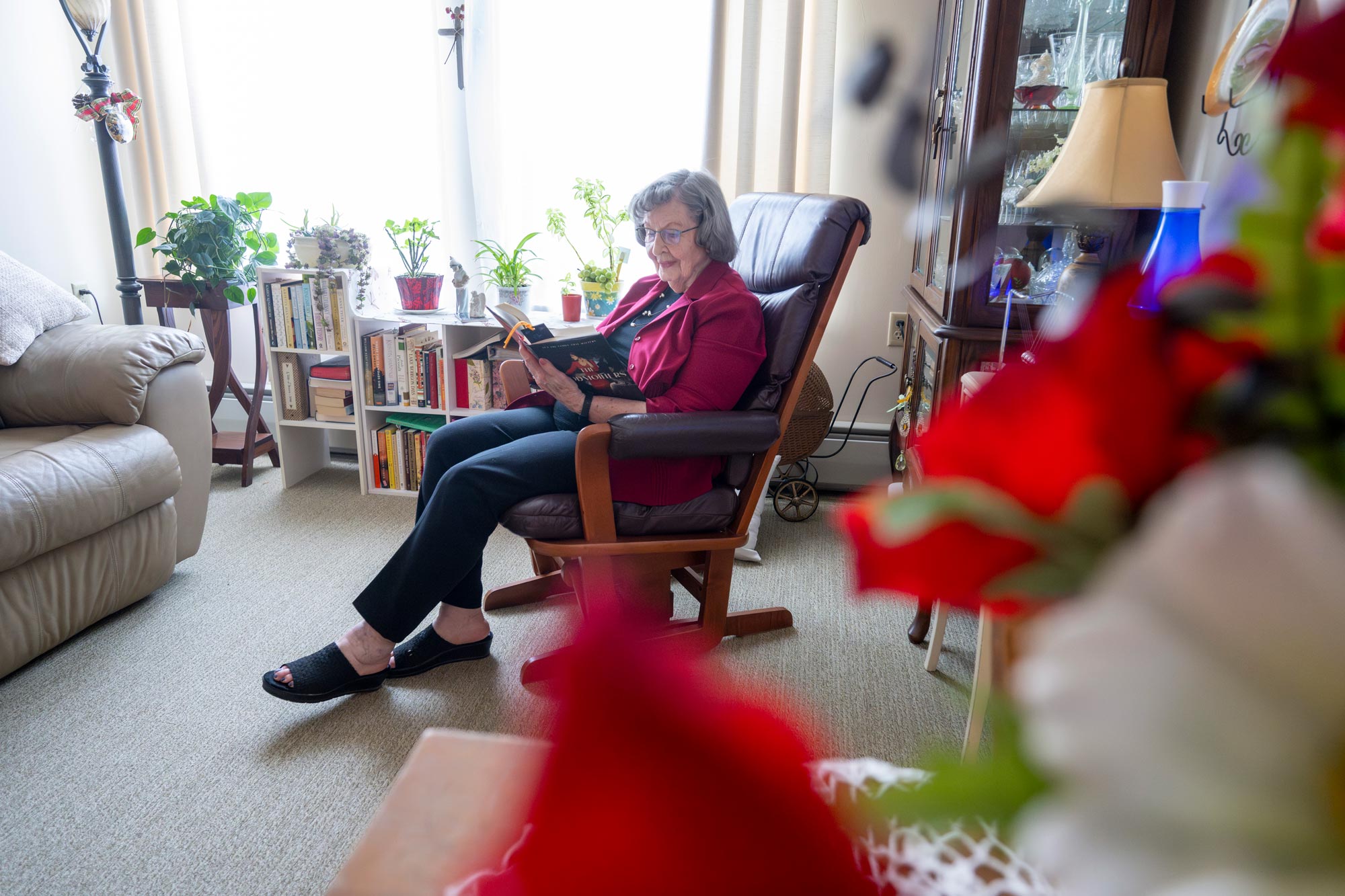 A Resident Reads in Her Rocking Chair in her Apartment