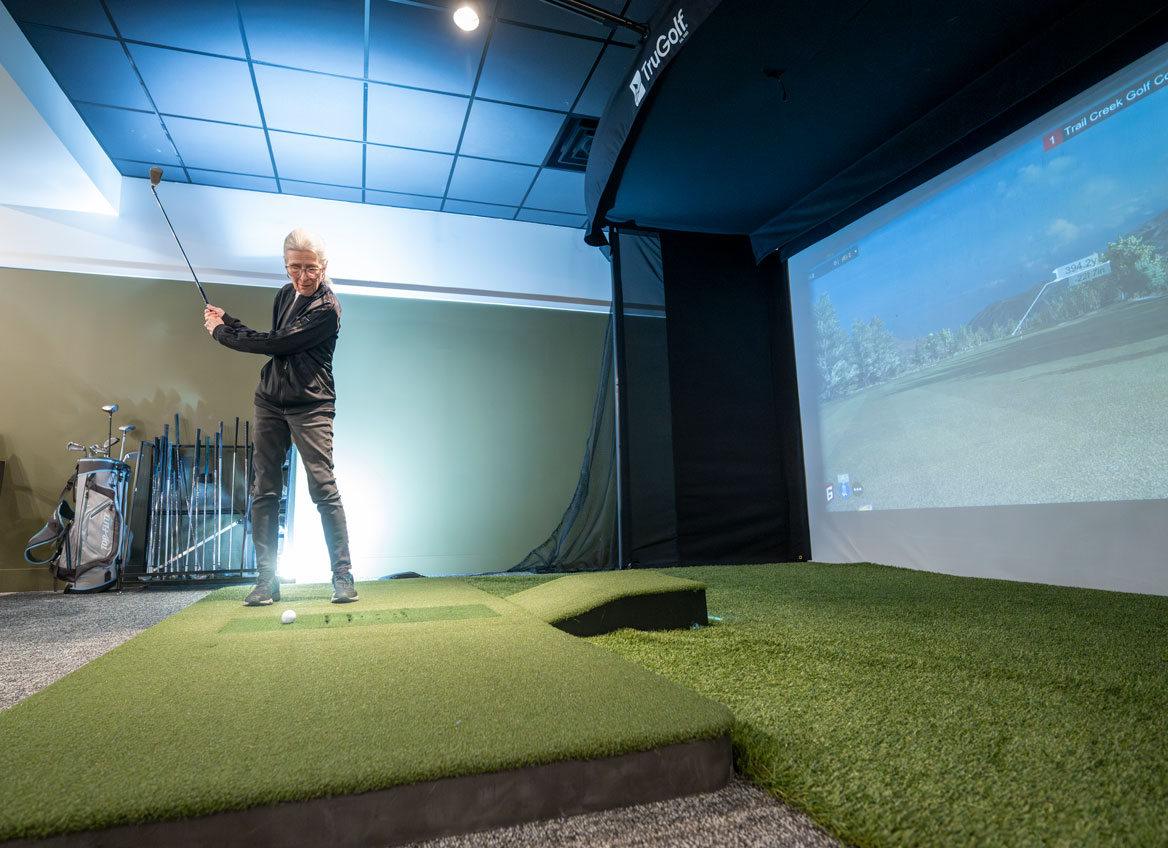 Resident Swings Her Club while using the Golf Simulator in the Game Room