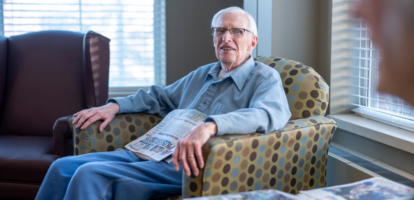 Resident of The Heritage at Lyngblomsten Reading and Chatting in the Lobby