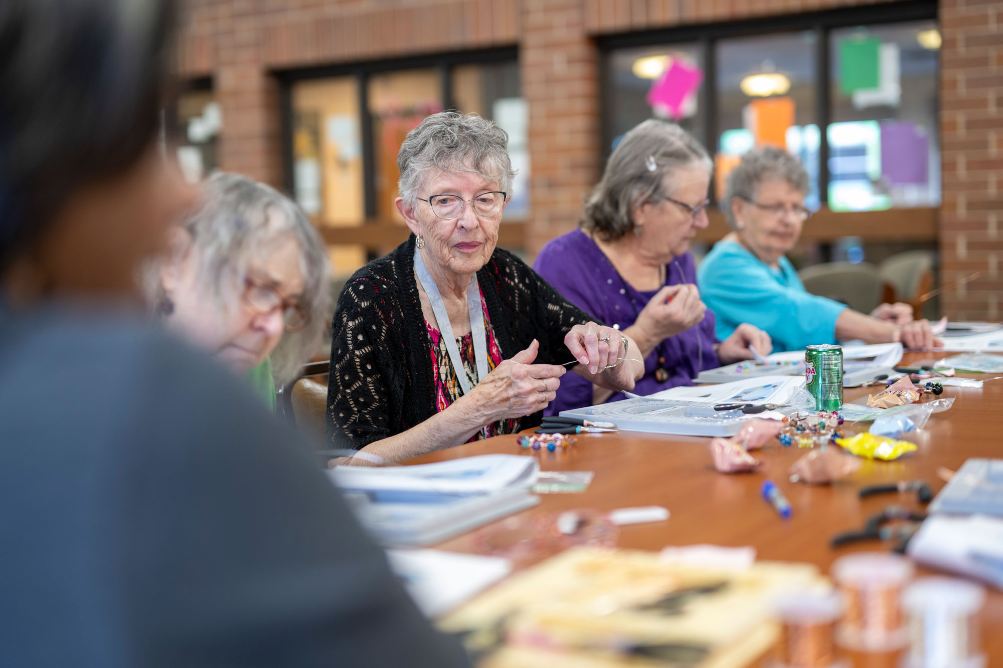 Residents Gather in the Dining Room to Create Jewelry with a Teaching Artist from COMPAS